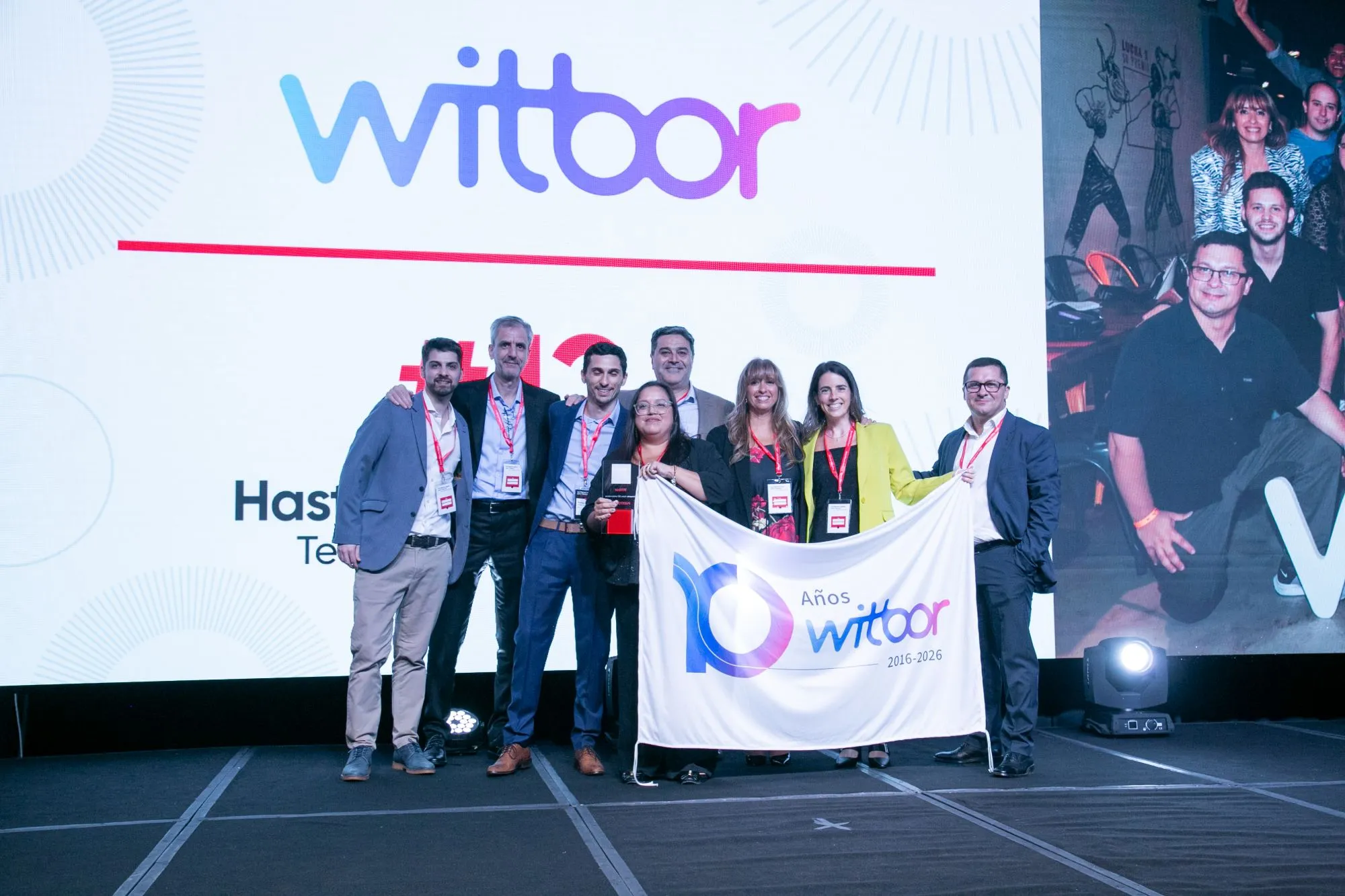 El equipo de Witbor con la bandera de los 10 años sobre el escenario de la premiación
